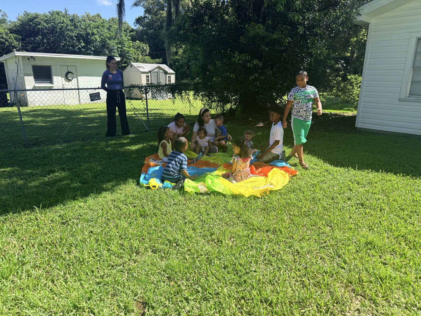 Children and teachers taking part in an outdoor parachute activity