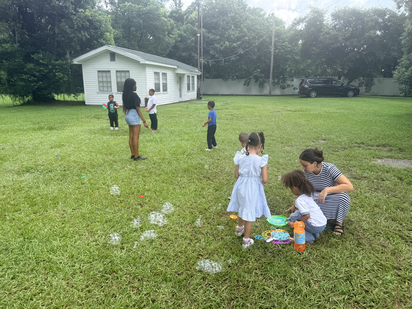 Children and teachers enjoying active outdoor play in the grassy yard